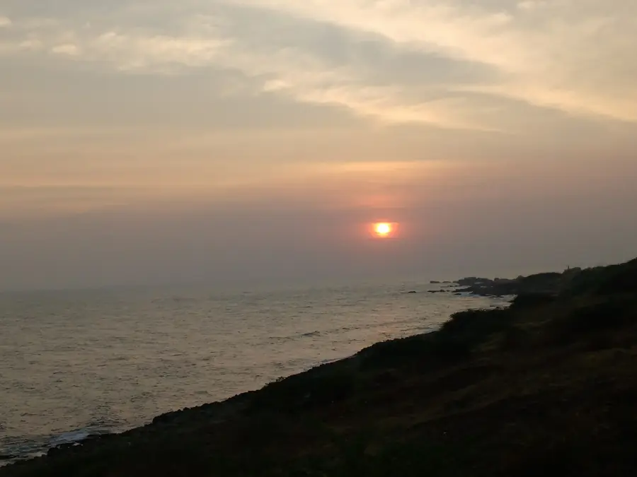 Silhouetted couple watching the sun set into the sea from the Kanyakumari promenade
